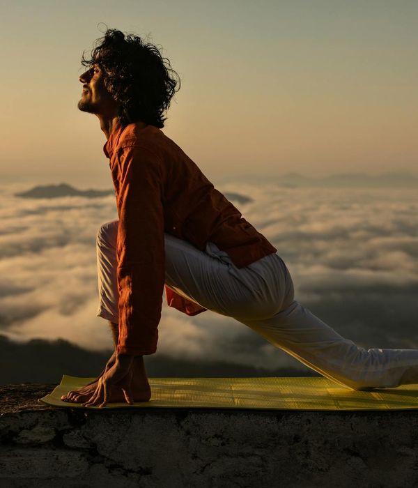 Silhouette of a man stretching against a sunrise.